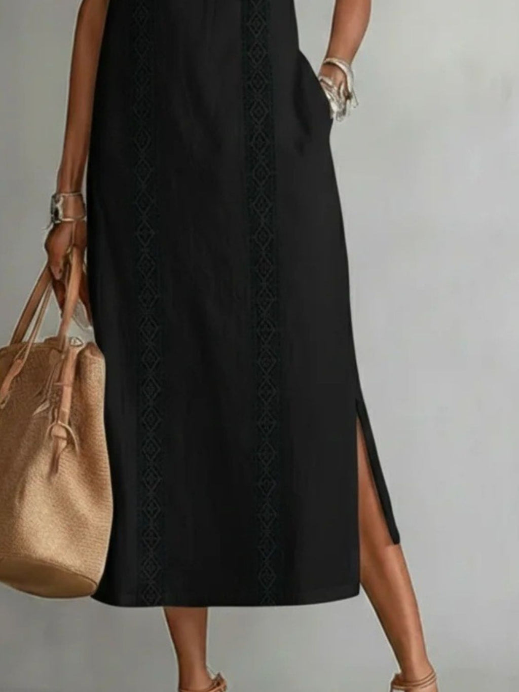Person wearing a black dress with a beige handbag on a plain background