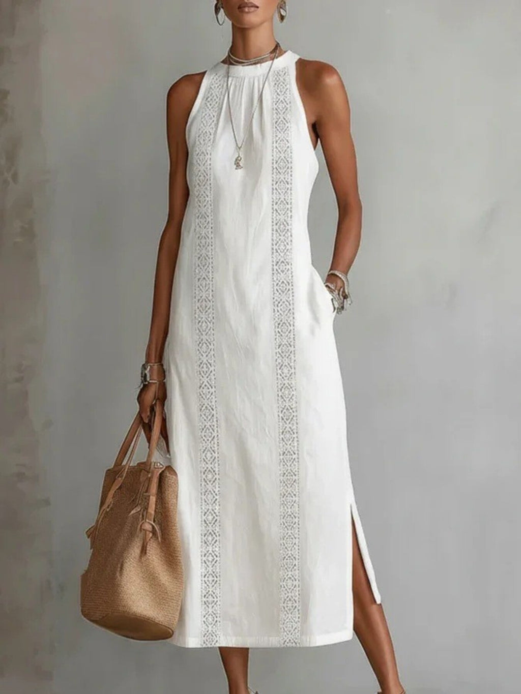 Woman wearing a white dress with embroidery holding a brown bag against a gray background